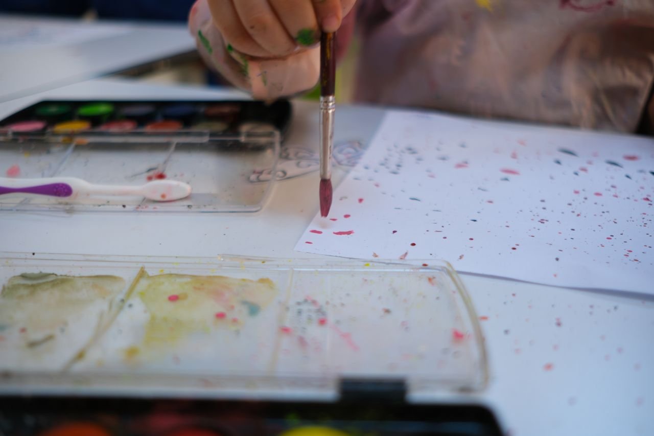 The Art of Drawing Readers In: Your attractive post title goes here A child painting with watercolors, creating art with vibrant splatters.