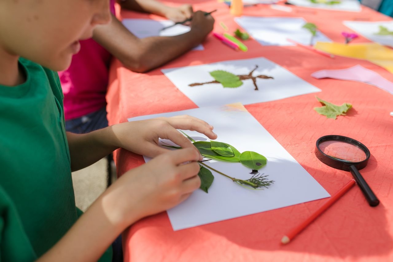 Crafting Captivating Headlines: Your awesome post title goes here Children create leaf art at summer camp, exploring creativity with natural materials.
