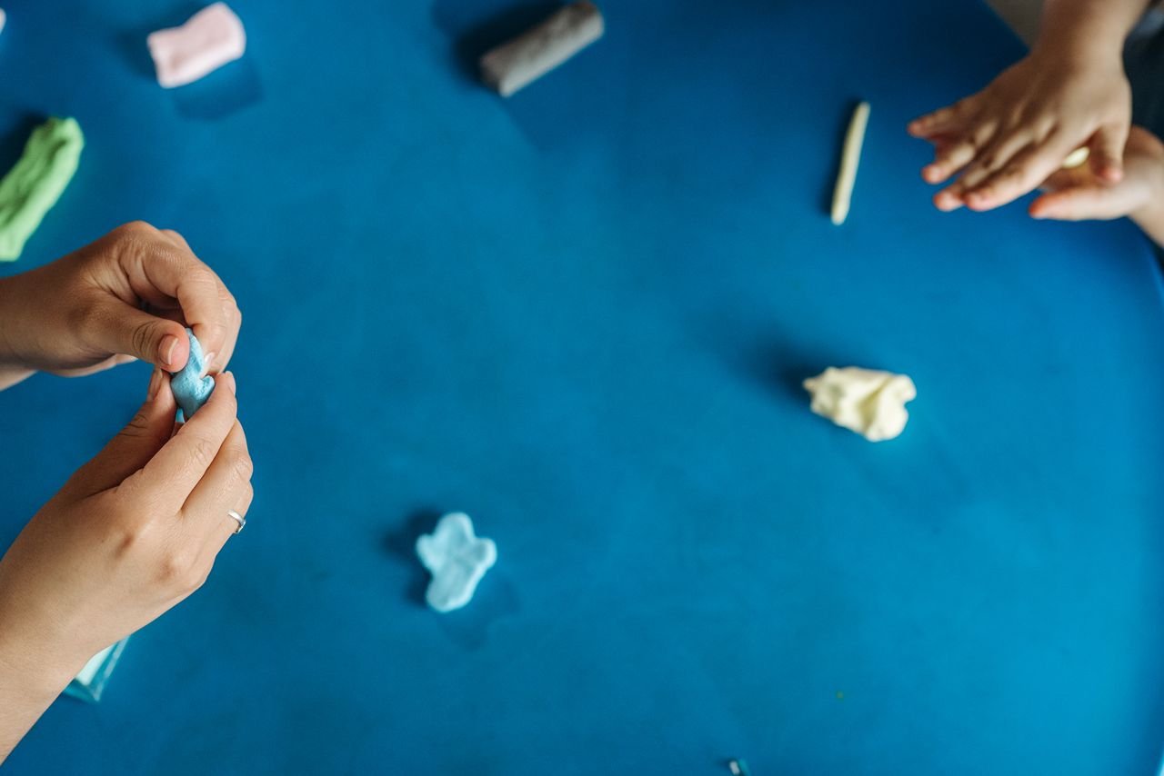 Mastering the First Impression: Your intriguing post title goes here Hands molding colorful clay on a blue table, capturing creativity and play in an artistic process.